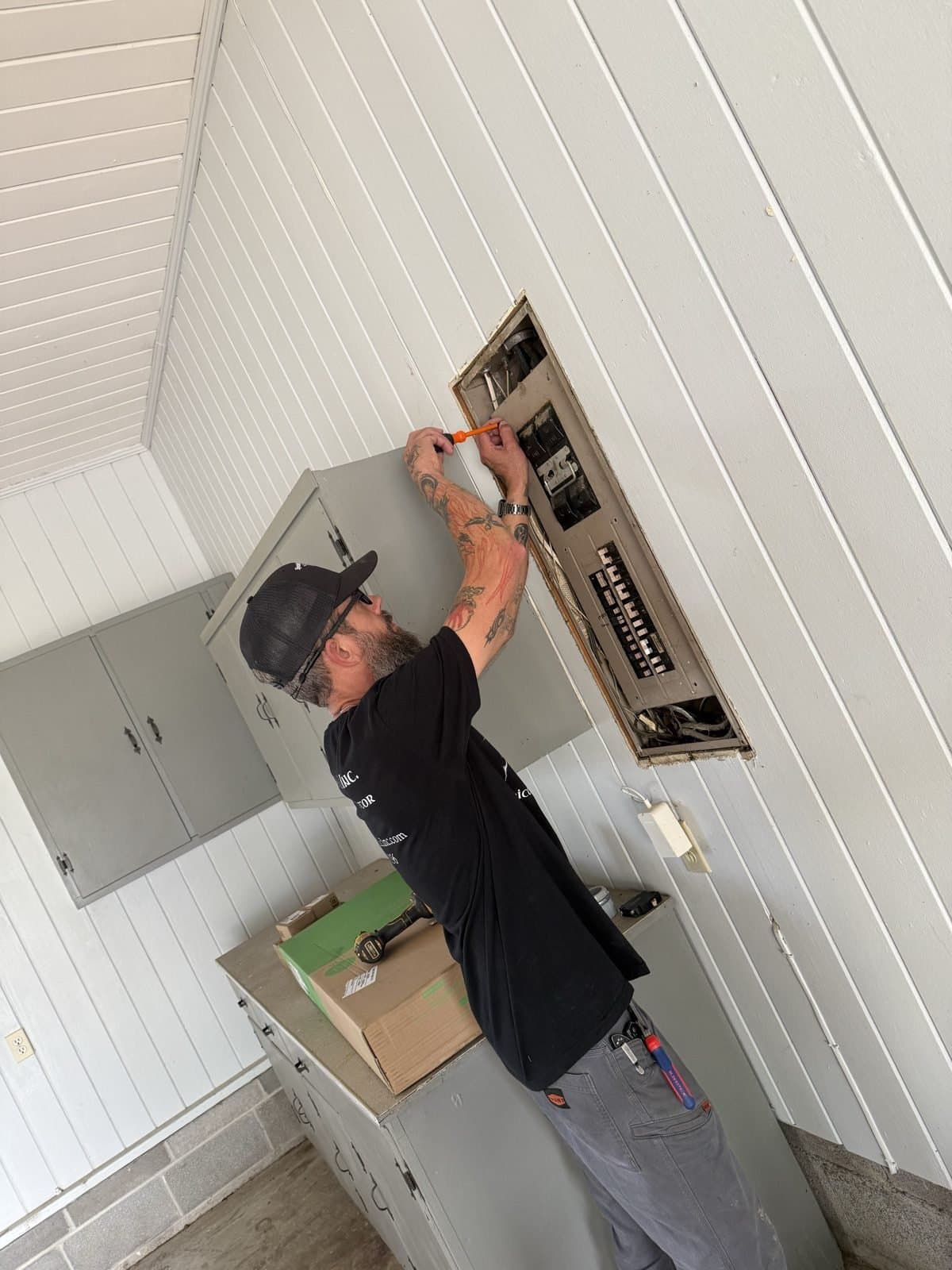 Spark Medic electrician wiring an overhead electrical panel on a job in North Alabama